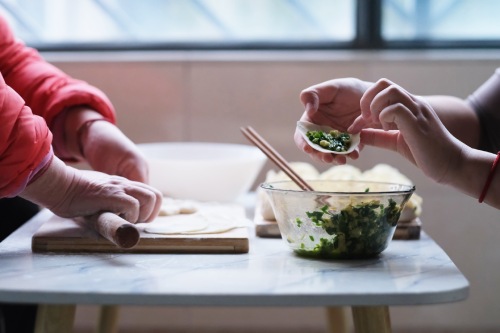 photo of people rolling dough for dumplings