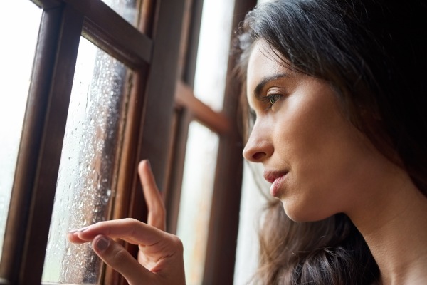 photo of sad woman looking out a rainy window